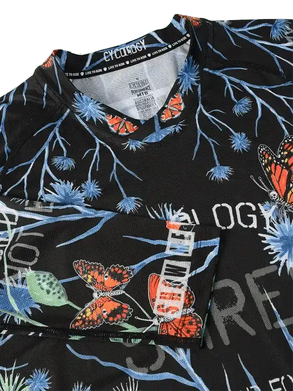 Black cycling jersey with blue floral and orange butterfly print, featuring 'Cycology' branding