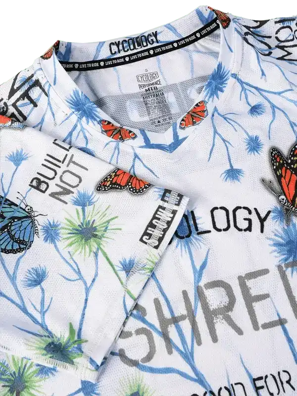 White cycling jersey with butterfly and floral print, bold text design, breathable fabric