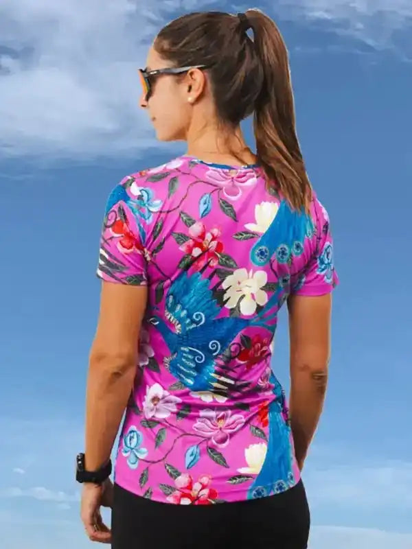 Woman wearing vibrant floral cycling jersey with blue sky backdrop