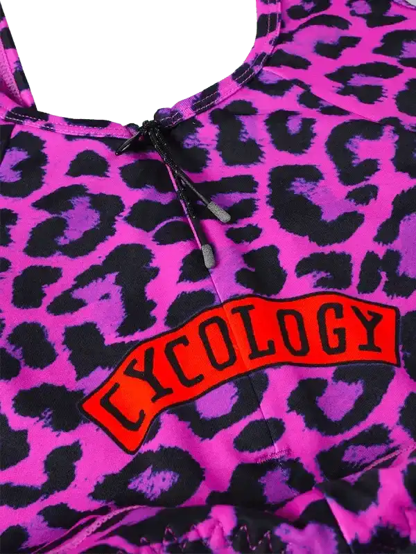 Vibrant pink leopard print cycling top with bold 'CYCOLOGY' logo, ideal for women's cycling apparel.