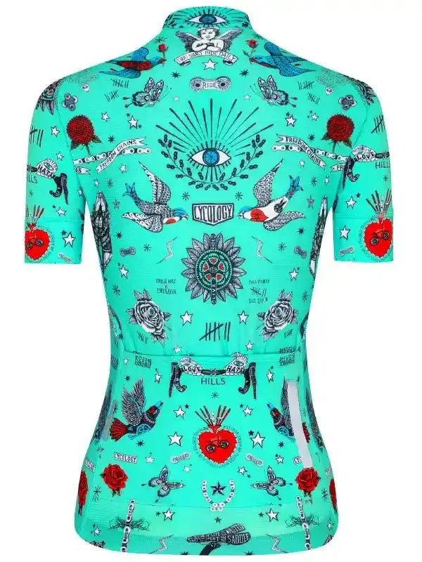 Turquoise women's cycling jersey with tattoo-style designs, roses, birds, and stars for road biking.