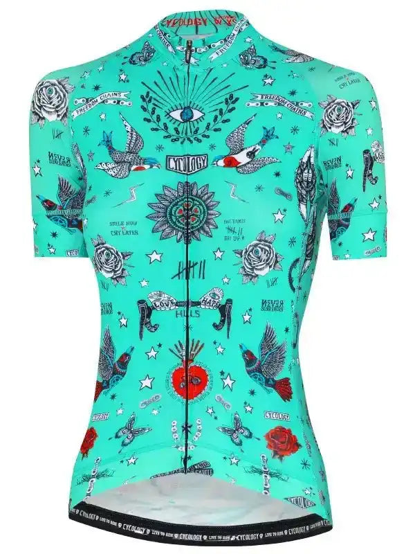 Mint green women's cycling jersey with tattoo-style roses, birds, stars, and eye design, featuring full zip and reflective hem.