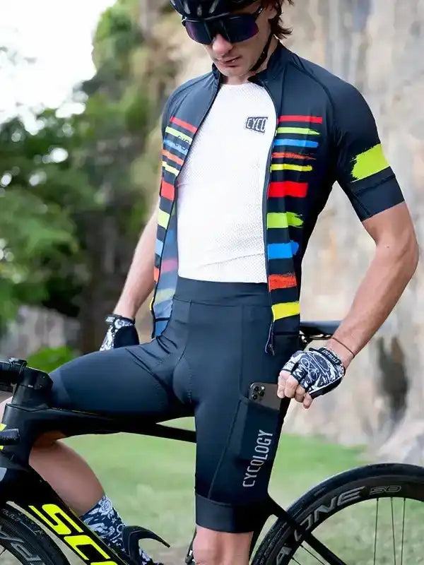 Men's cycling jersey with colorful stripes, black shorts, and gloves, riding a road bike outdoors