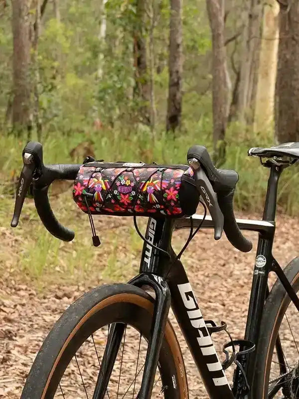 Floral bike handlebar bag on black road bike in forest trail, cycling gear for outdoor rides