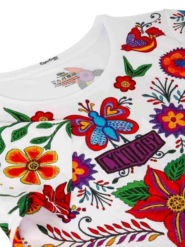 White cycling jersey with vibrant floral and butterfly embroidery, featuring colorful patterns and brand tag.