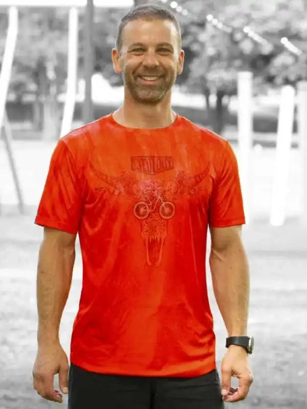 Man wearing vibrant red cycling t-shirt with skull and bike graphic, ideal for men's cycling apparel