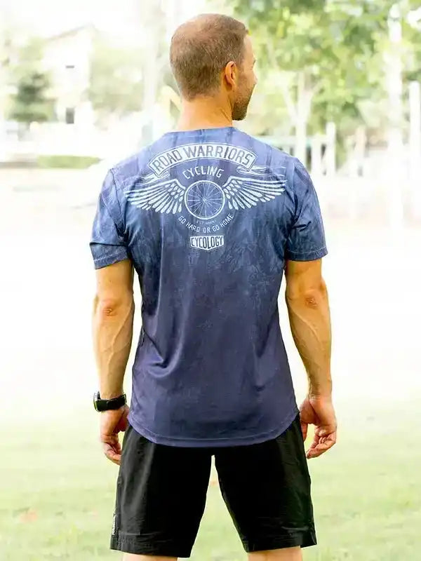 Men's cycling t-shirt with 'Road Warriors' graphic, wings, and bike wheel design, worn outdoors