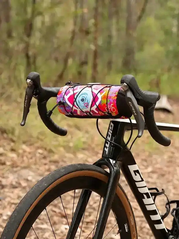 Colorful cycling handlebar bag with eye design on road bike in forest setting