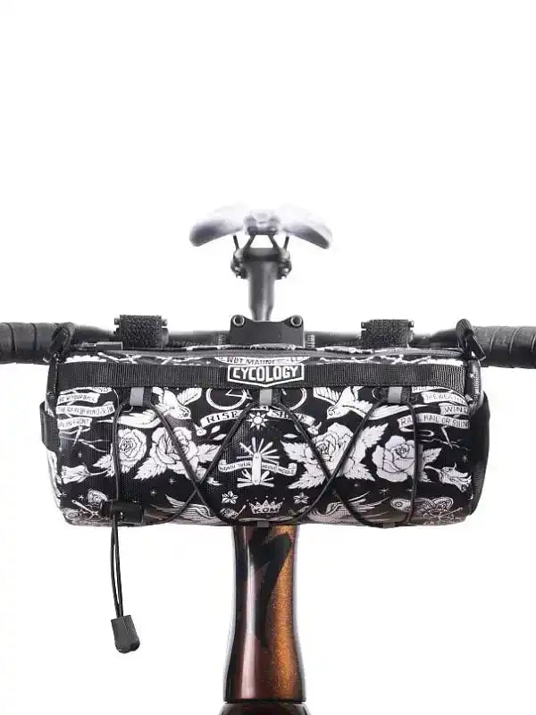 Black and white tattoo-style cycling handlebar bag with roses and wings, mounted on bike