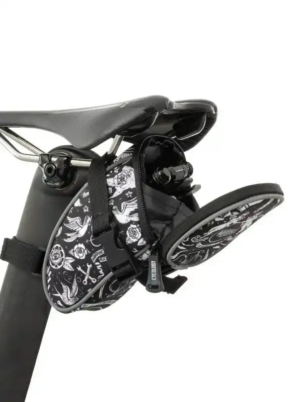 Black and white floral patterned cycling saddle bag attached to bike seat, ideal for road or mountain biking gear storage.